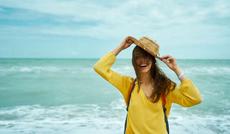Authentic summer beach portrait positive girl holding over had straw hatの写真素材