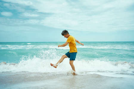 Cheerfulness man having fun at sea or ocean beach, splashing waterの写真素材
