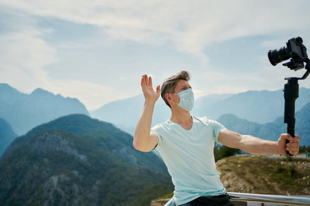 Travel man making content video on camera for travel blogg, wearing protective face mask, standing in front of mountains. Tunektepe Teleferik, Antalyaの写真素材