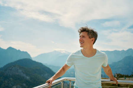 Positive happy man tourist enjoying fresh air at viewpoint among mountains and cloudy sky. travel to the mountains region of Turkeyの写真素材