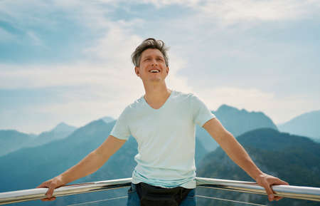 Joyful traveler man looking up and feeling freedom on top of mountains. Adventure and travel exploringの写真素材