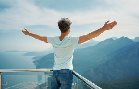 Rear view male with raised hands at viewpoint of mountains Tunektepe Teleferik, Antalya, Turkey. Summer journey vacationの写真素材