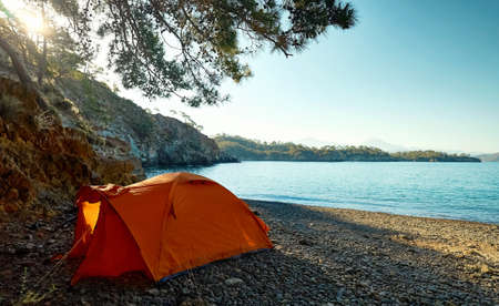Morning in Camping with orange tent at wild beach of Mediterranean seashore during sunrise, beautiful nature landscapeの写真素材