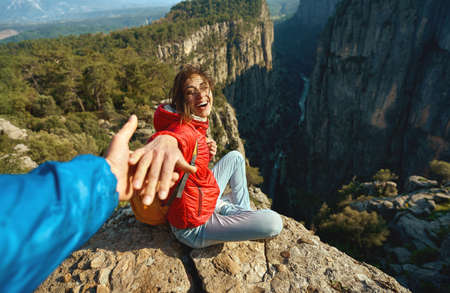 Portrait happy laughing woman sitting by the cliff and holding someone hand. People on hiking journey at Tazi canyon, Turkeyの写真素材