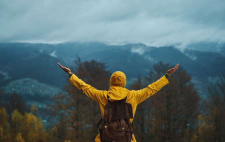 Woman traveler enjoying view of mountain summit and success raised hands up. Travel adventure hiking with backpack outdoor, active vacationの写真素材