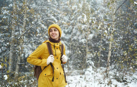 Woman walking alone in winter forest, enjoying wilderness, wearing yellow winter clothes and backpack. Winter is comingの写真素材