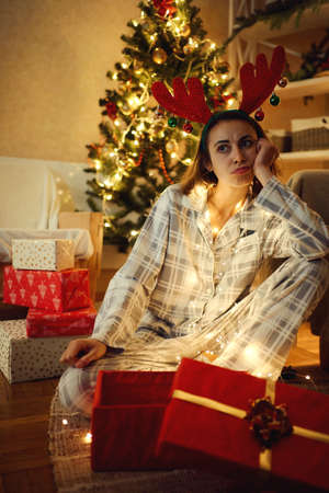 Unhappy disappointed woman feeling bored and getting bad presents on Christmas or New Year holidaysの写真素材
