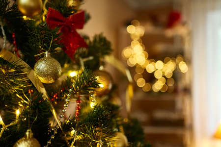 Close up decorated Christmas tree with golden balls, xmas toys, lights, glowing lamps in living room. Bokeh garlands on backgroundの写真素材