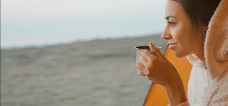 Close-up portrait carefree woman holding mug and enjoys morning in camping in tent. Calmness and...