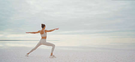 Panoramic view infinity salt lake and sky, sporty woman doing yoga exercise. Harmony nature and peole conceptの写真素材