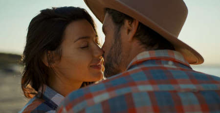 feelings love concept, beautiful woman kissing man in hat at sunset. sweety lovely moments of couple in loveの写真素材