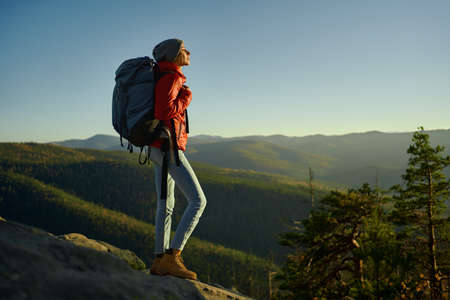 young confident woman enjoying nature and looking confident and happy with her hiking expedition outdoors on top of mountain at sunset.の写真素材