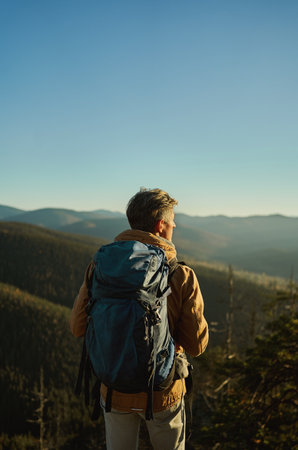 Nature view of mountains and hills with woods at sunset, back view man hiker admiring landscape, travel point destinationの写真素材