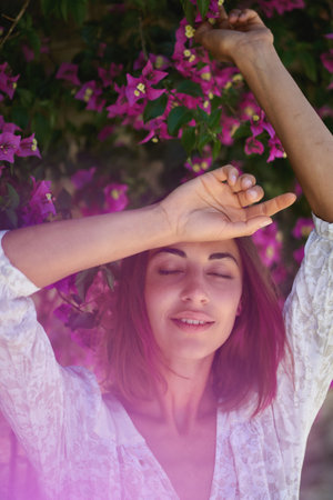 Spring beauty portrait stunning young woman posing with clothing eyes in garden with pink flowersの写真素材