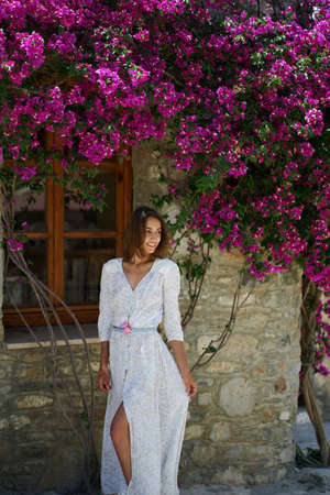 Beauty sensual woman in elegant dress standing near old house surrounded by violet flowersの写真素材
