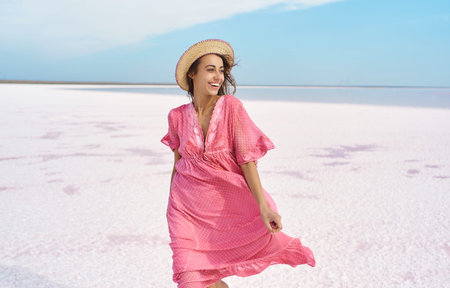 Beautiful happy woman emotionally smile to camera, wearing pink dress, enjoying time on desert beach...