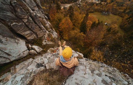 Top view alone hiker man with backpack sitting in cliff and enjoying fall landscape in valley. Popular tourist place in Ukraine, Tasman National Parkの写真素材