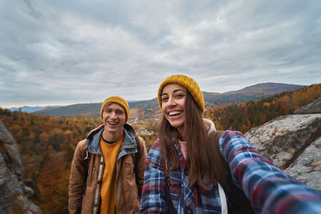 Happy tourist couple making selfie with nature view during travel together, enjoying active lifestyle vacations outdoorsの写真素材