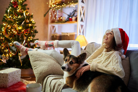 Pleased woman enjoying on winter holiday. Happy celebrating Christmas together wit pet Corgi dogの写真素材