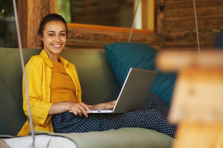 Portrait young smiling woman freelance worker or student working remotely from summer cafe on laptop computerの写真素材