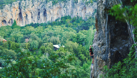 Panoramic landscape view of beautiful canyon with strong man climbing on challenging route on rockの写真素材