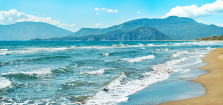 Seascape with waves at sunny day at beautiful sandy empty beach. Beautiful mountain range on background. Iztuzu in Turkeyの写真素材