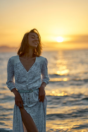 Attractive sensual young woman posing in front of sea at beautiful sunset. Nature and beauty conceptの写真素材