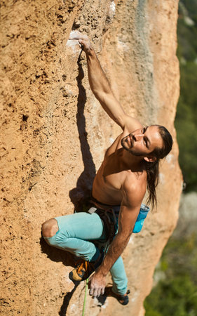Rock climbing moments. Top view of beautiful athletic male confidently looking up on rockの写真素材