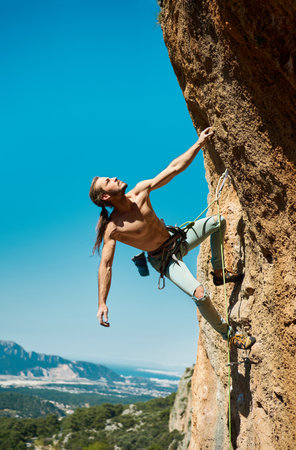 Power and energy in human body. Athletic confidence man climber looking up and gripping hold. Rock climbing and active lifestyle conceptの写真素材