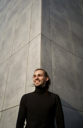 Urban simplicity and minimalism contemporary. Portrait of joyful smiling man against gray wall with symmetrical lines outsideの写真素材