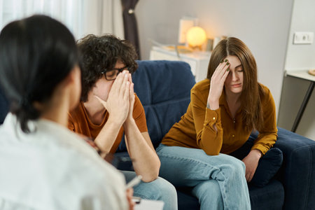 Marital Psychotherapy. Psychologist sitting back to camera during a meeting with patients in office. Unhappy disappointed couple trying to save their relationship and avoid divorce. Selective Focusの写真素材