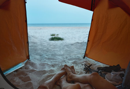 View from camping tent on morning landscape on serenity beach and two people travelers lying inside tentの写真素材
