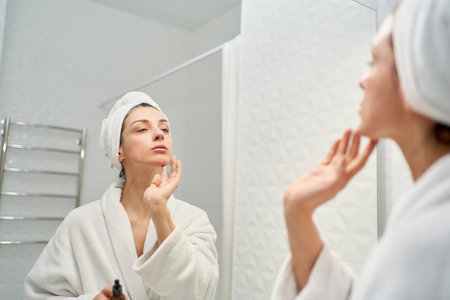 Beautiful lady delicately applying facial serum as part of her skincare routine.Perfect for beauty and skincare related projectsの写真素材