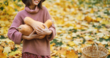 Close up hands of woman embracing rape pumpkins surrounded orange leaves, enjoying autumnal time and seasonal harvestの写真素材