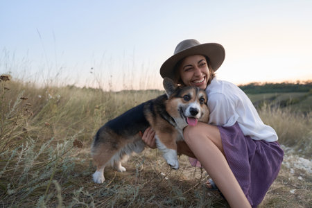 Cute funny Welsh Corgi dog embracing with owner woman amidst a vibrant fieldの写真素材