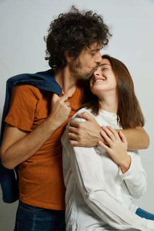 Portrait of young passionate couple cheerfully embracing and kissing against a clean white backgroundの写真素材
