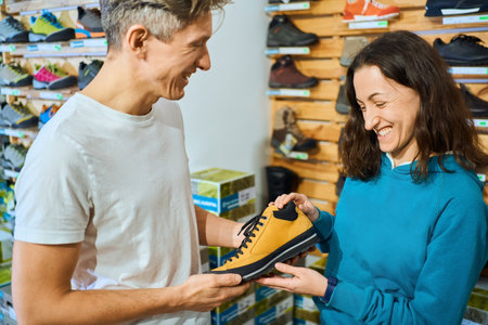 Charming woman sales consultant presentation to man client the perfect pair of shoes in shoe store.の写真素材
