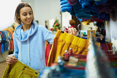 Pretty joyful woman choices colorful pants in clothing shop , selecting the perfect fitの写真素材