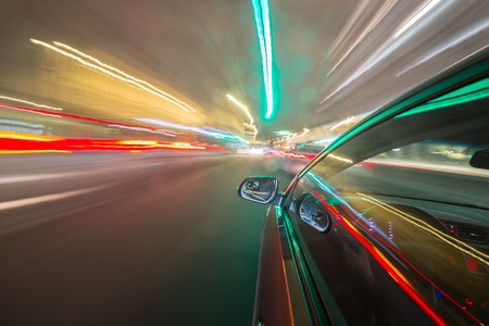 View from Side of Car moving in a night city, Blured road with lights with car on high speed. Concept rapid rhythm of a modern city.の写真素材