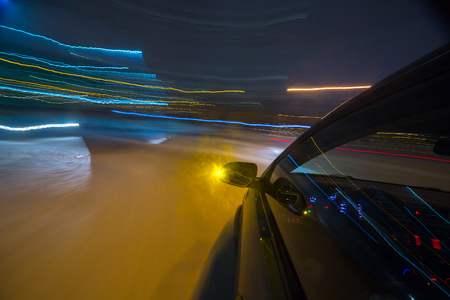 View from Side of Car moving in a night city, Blured road with lights with car on high speed. Concept rapid rhythm of a modern city.の写真素材