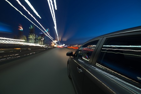 View from Side of Car moving in a night city, Blured road with lights with car on high speed. Concept rapid rhythm of a modern city.の写真素材