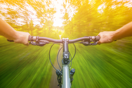 Mountain biking down hill descending fast on bicycle with motion blur. View from bikers eyes.の写真素材