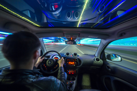 Urban high spees driving on a smal city car with panoramic roof. View from inside car natural light street and other cars is motion blurred.の写真素材