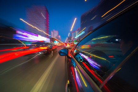 View from Side of Car moving in a night city, Blured road with lights with car on high speed. Concept rapid rhythm of a modern city.の写真素材