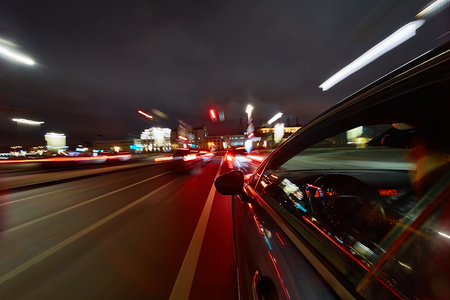 View from Side of Car moving in a night city, Blured road with lights with car on high speed. Concept rapid rhythm of a modern city.の写真素材