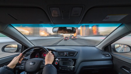 City road view from inside car natural light street and other cars is motion blurredの写真素材