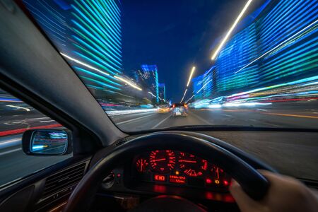 Movement of the car at night at high speed view from the interior with driver hands on wheel. Concept spped of life.の写真素材