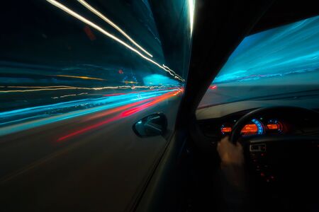 Movement of the car at night at high speed view from the interior with driver hands on wheel. Concept spped of life.の写真素材