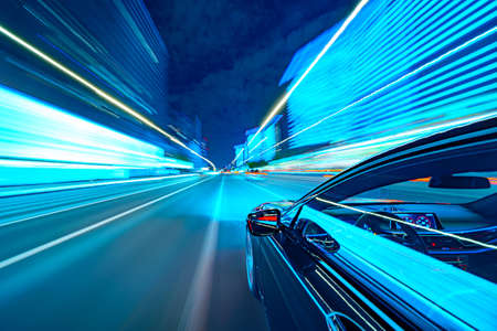 View from Side of a Black Car moving in a night city, Blured road with lights with car on high speed. Concept rapid rhythm of a modern city.の写真素材