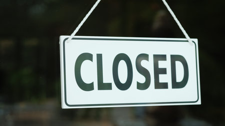A sign with the words closed on the glass door of the store